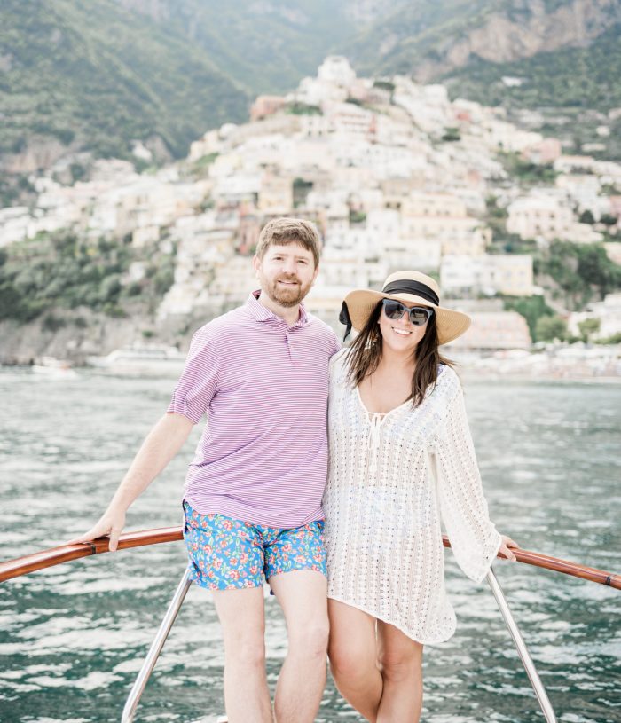 John and Brittney Naylor posing on private boat with Positano behind them